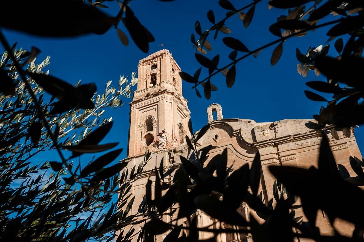 L'església del Poble Vell de Corbera d'Abre vista entre branques d'olivera