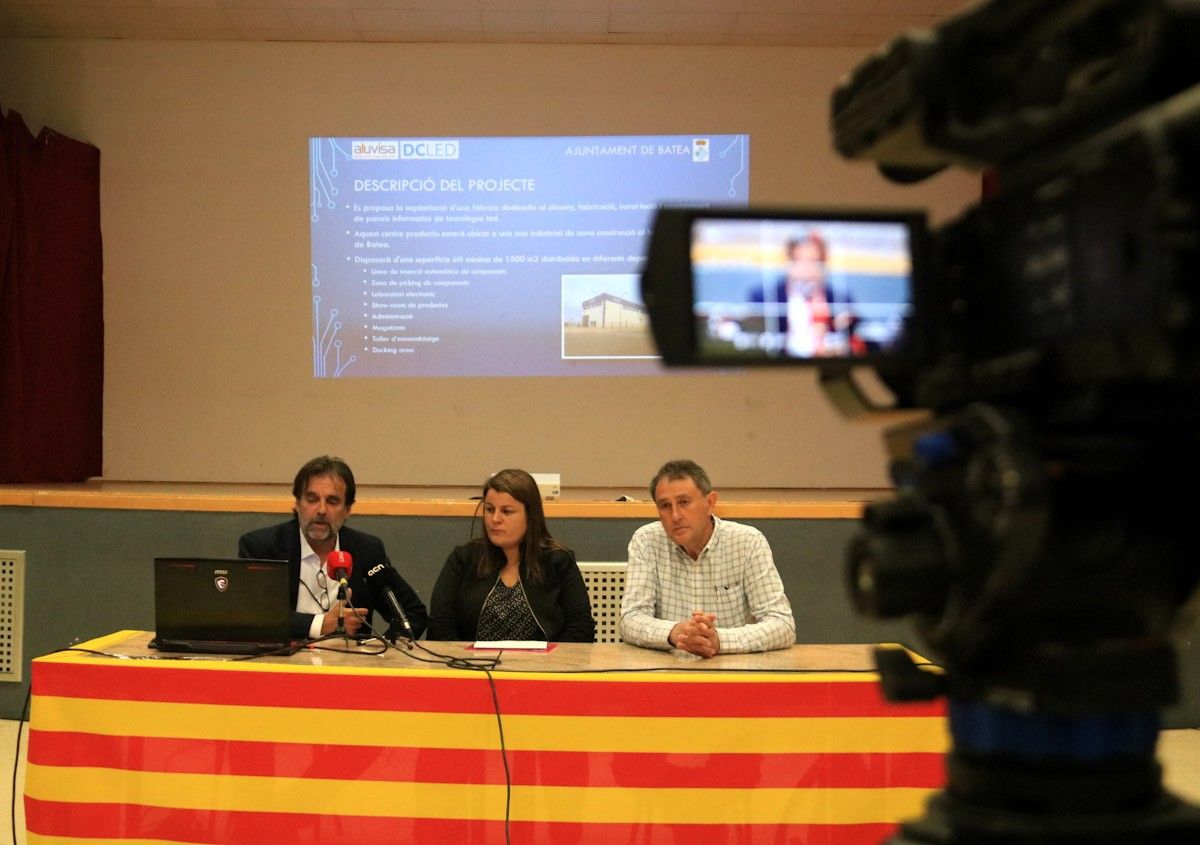 Una càmera grava l'acte electoral d'UPTA, amb el candidat Joaquim Paladella, i Antoni Muñoz, director comercial del grup Aluvisa, per anunciar el compromís de l'empresa de construir al municipi una fàbrica de panells informatius LED.  