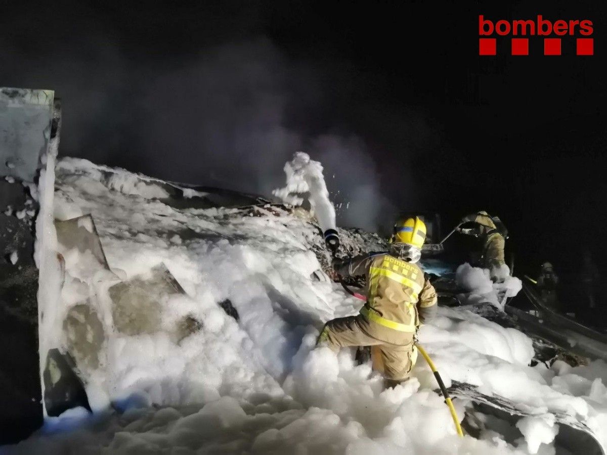 Els Bombers extingint el foc del camió, que ha bolcat a l'AP-7 a Ulldecona.