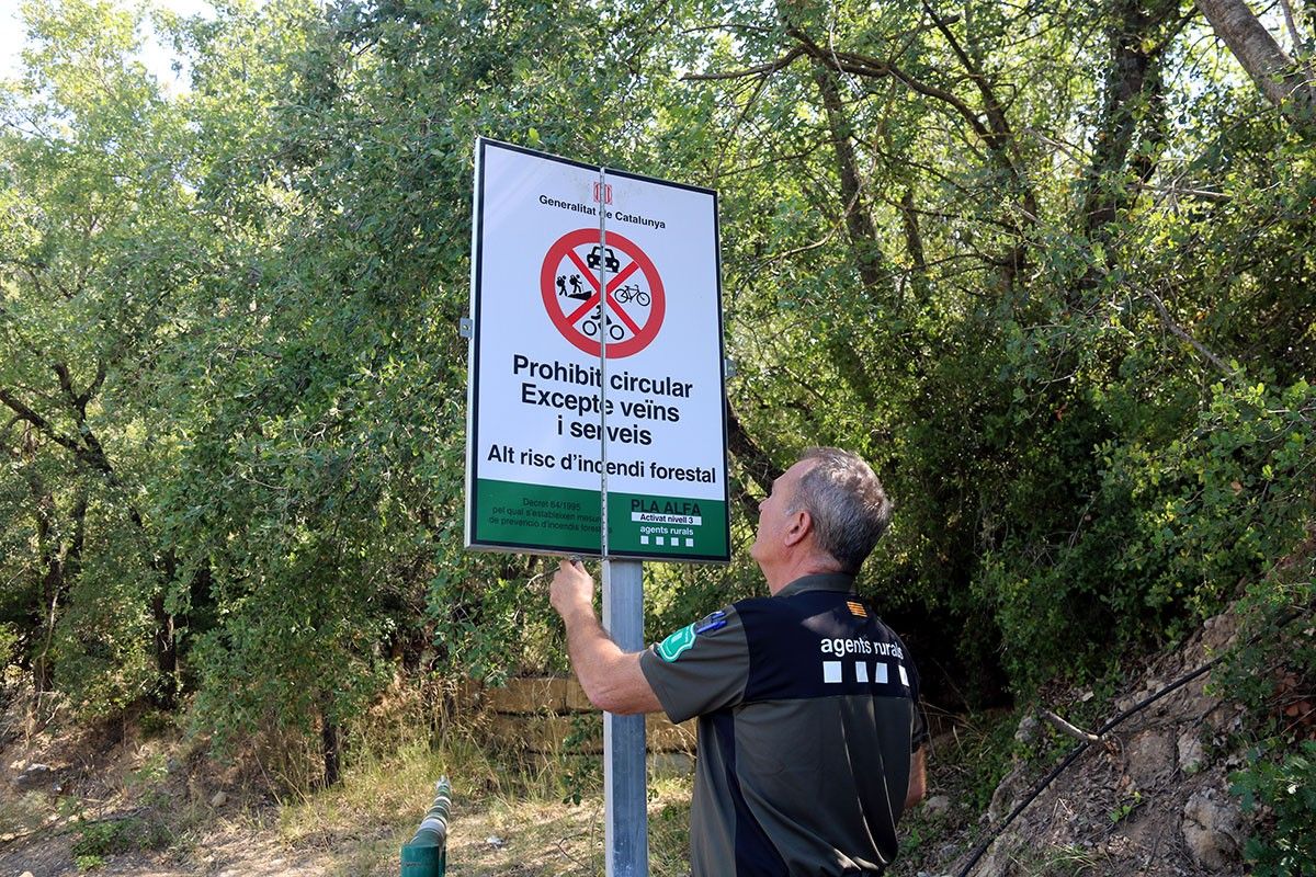 Un Agent Rural obre un cartell de prohibit el pas.