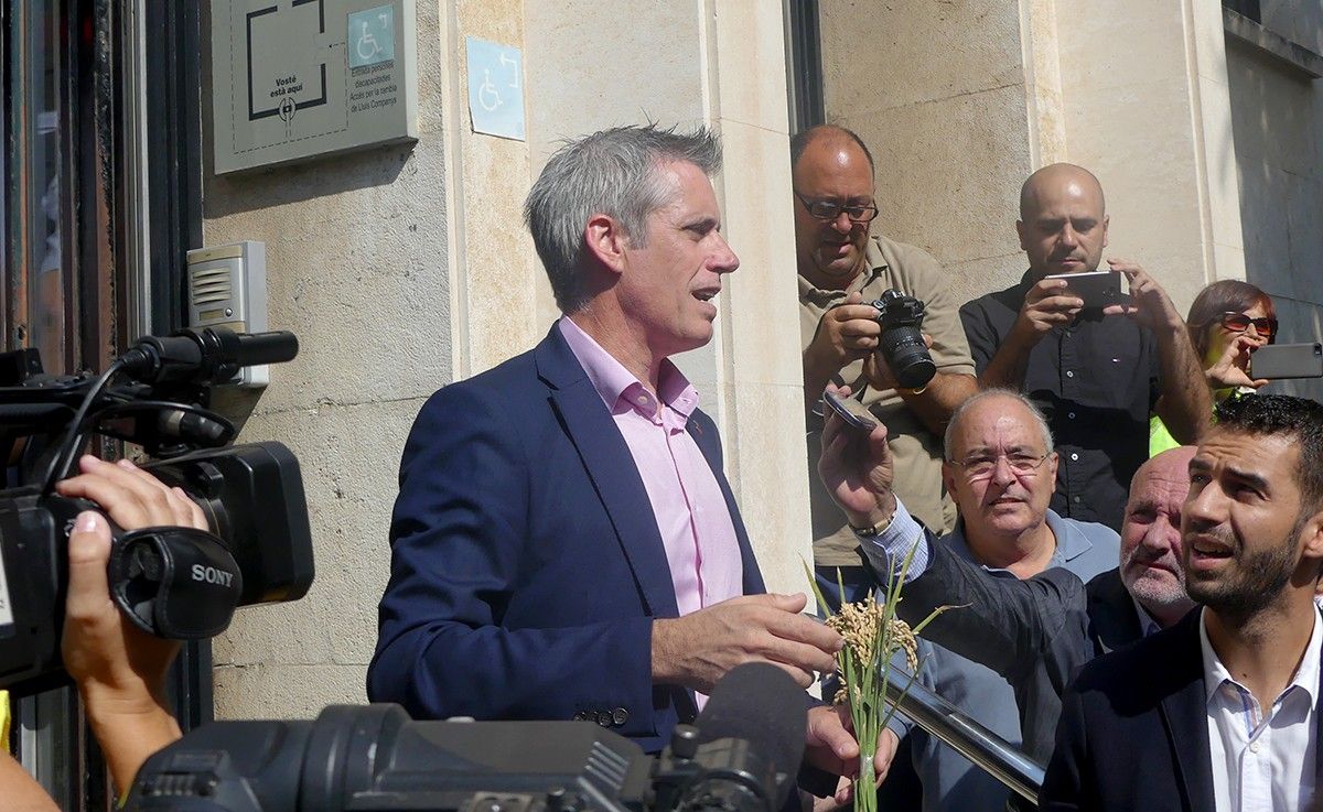 Adam Tomàs a les portes de l'Audiència de Tarragona amb una garba d'arròs a les mans.