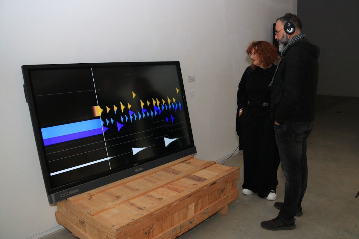 Dos espectadors escolten l'obra 'Contorns', en el marc de l'exposició 'FORMS - música visual generativa' a Lo Pati - Centre d'Art de les Terres de l'Ebre  
