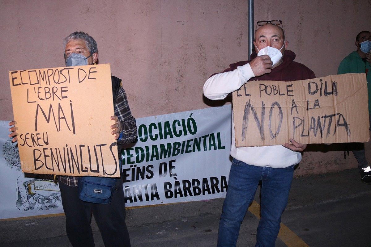 Dos veïns xiulant i mostrant pancartes en contra de la concessió de la llicència ambiental al projecte de planta de compostatge davant de l'Ajuntament de Santa Bàrbara  
