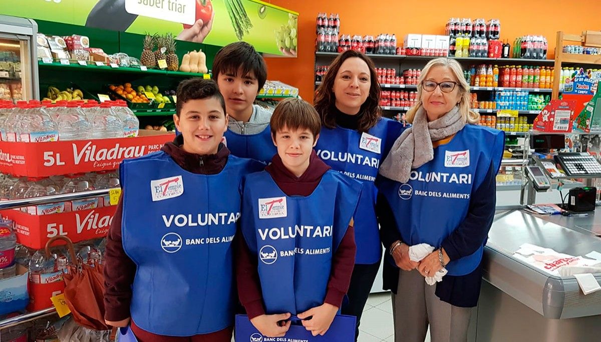 Alguns alumnes de l'escola del Temple amb voluntaris adults recollint aliments en un supermercat de Tortosa.