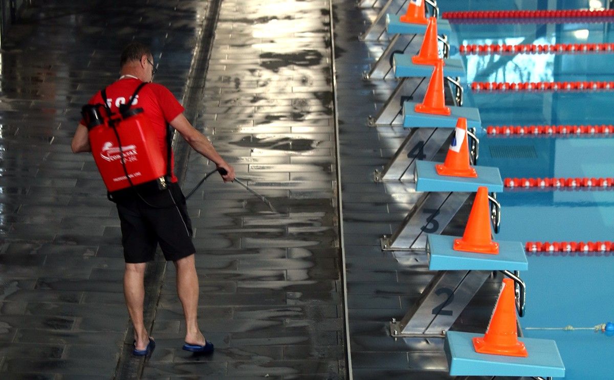 Un tècnic del complex esportiu Win de Tortosa desinfectant entre torns d'usuaris els espais de la piscina. 