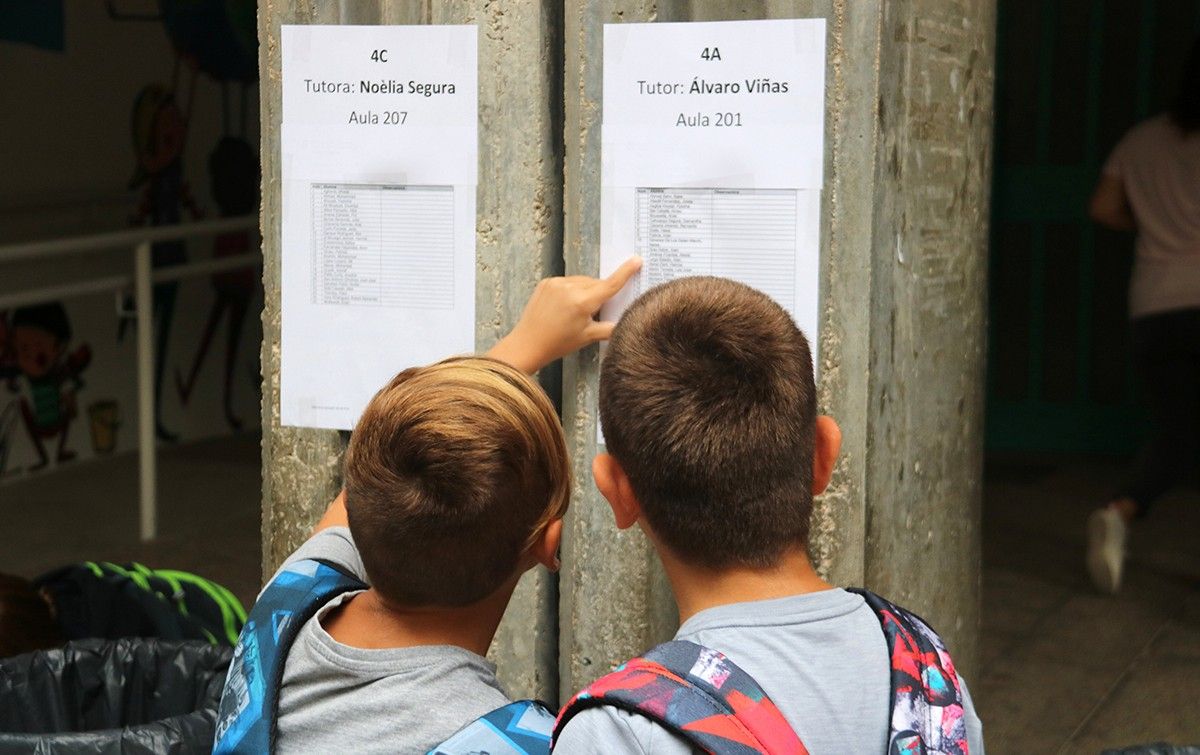 Dos xiquets observant la llista d'alumnes per aula a l'entrada de l'escola de Ferreries, a Tortosa.