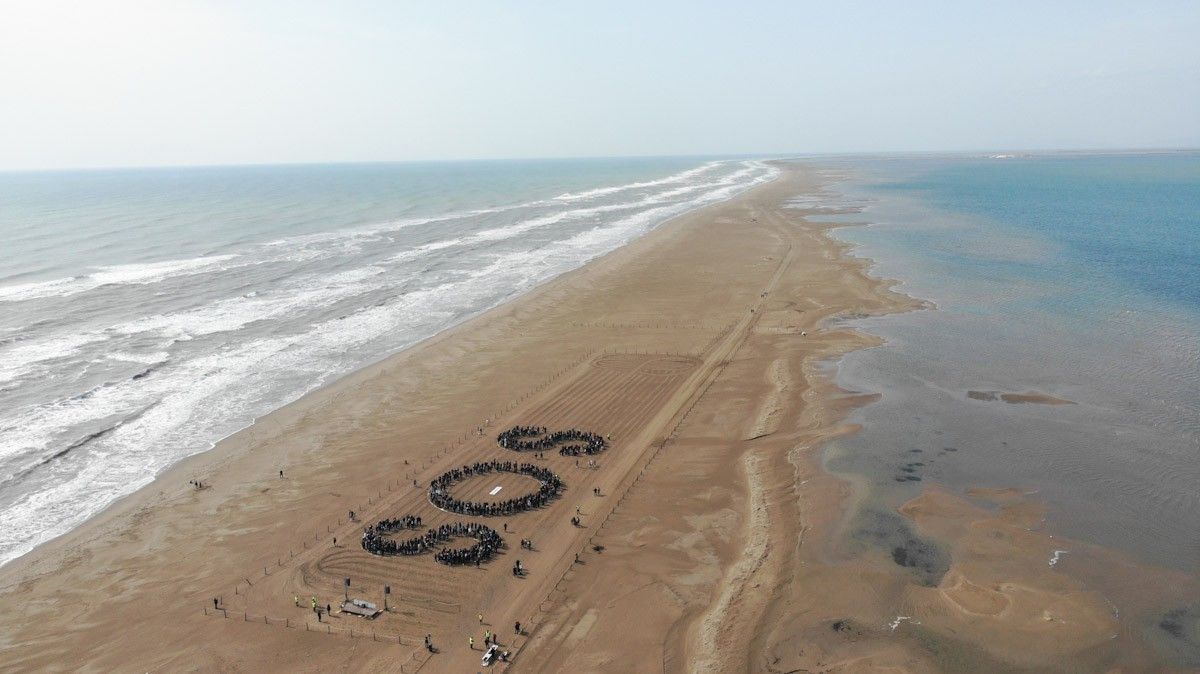 Els assistents a l'acte del MOLDE han configurat les lletres SOS a la platja del Trabucador