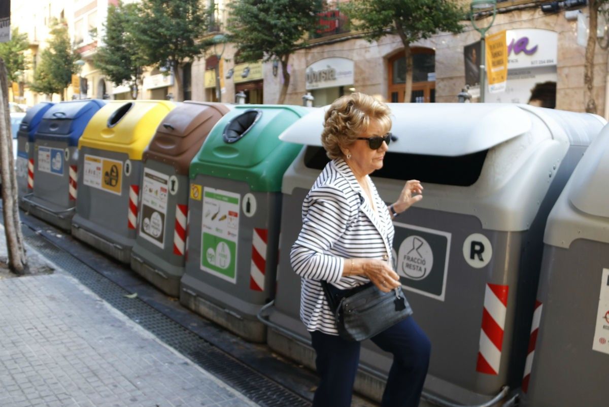 Una dona que obre un contenidor de brossa per llençar-hi un residu.