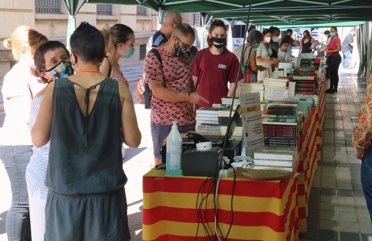 Clients remenant la parada al carrer que la llibreria La 2 de Viladrich ha preparat per al Sant Jordi d'estiu a Tortosa. 