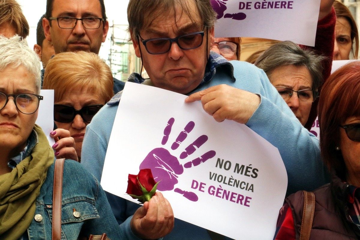 Un home mostrant un cartell contra la violència masclista i una rosa roja, en la concentració a Ulldecona de rebuig per l'assassinat d'una jove veïna de Vinaròs.