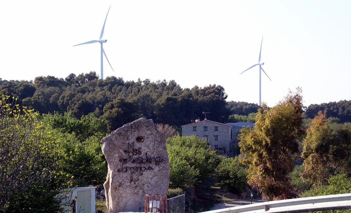 Una casa rural entre la Fatarella i Vilalba dels Arcs amb dos aerogeneradors al fons