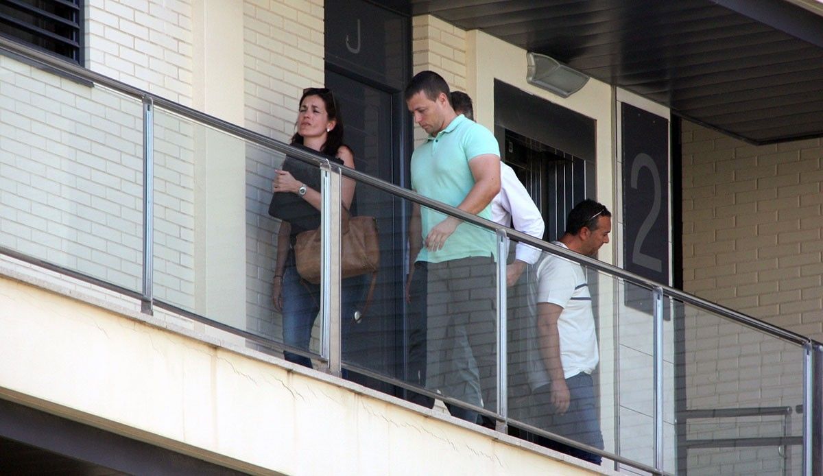 Andreu Martí, amb camisa blanca de màniga llarga, darrera un agent de la Guàrdia Civil i acompanyat per al secretària judicial arribant al seu pis per registrar-lo..