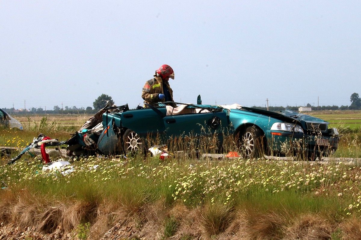 Un bombers al costat del turisme en el qual viatjaven les dos víctimes de l'accident a la TV-3405, a Amposta.