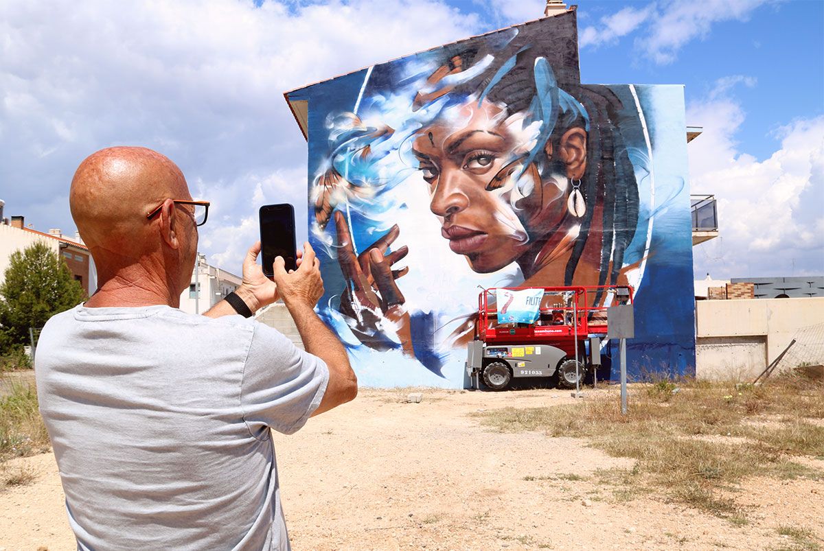 Un veí de l'Ametlla de Mar fa una foto a un mural de l'artista Filite.