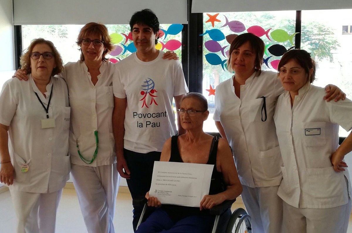Lourdes Seller fa entrega del xec per valor de 450 euros a l'ONG Provocant la Pau, acompanyada de personal sanitari de l'Hospital de Jesús.