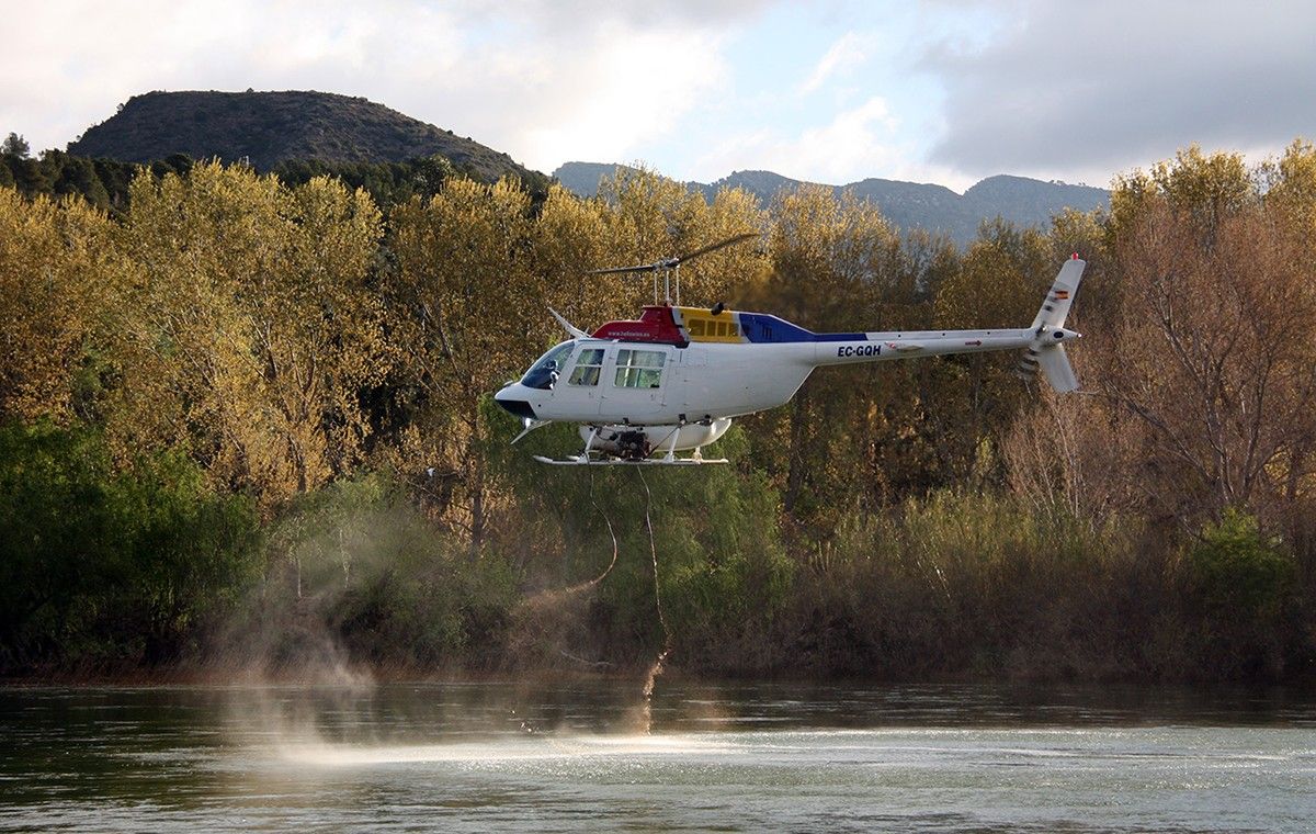 Un helicòpter buidant la càrrega d'insecticida biològic BTI al riu Ebre, a l'alçada de l'assut de Xerta 