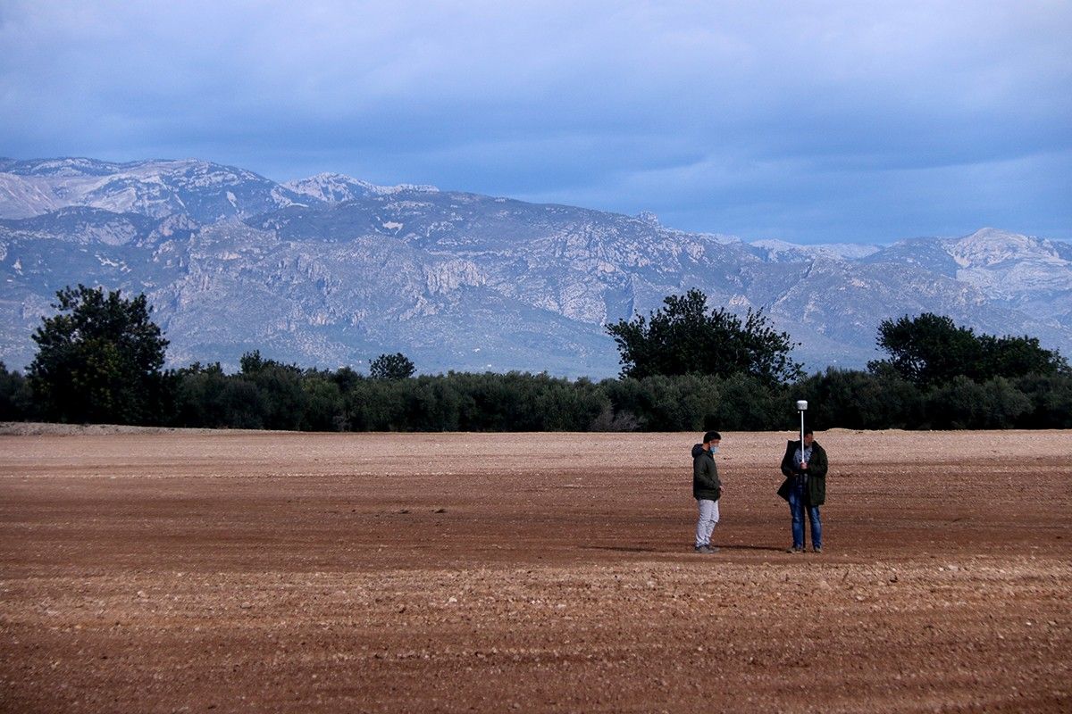 Els terrenys on es projecta la planta de compostatge a Santa Bàrbara amb dos persones prenent mesures del terreny