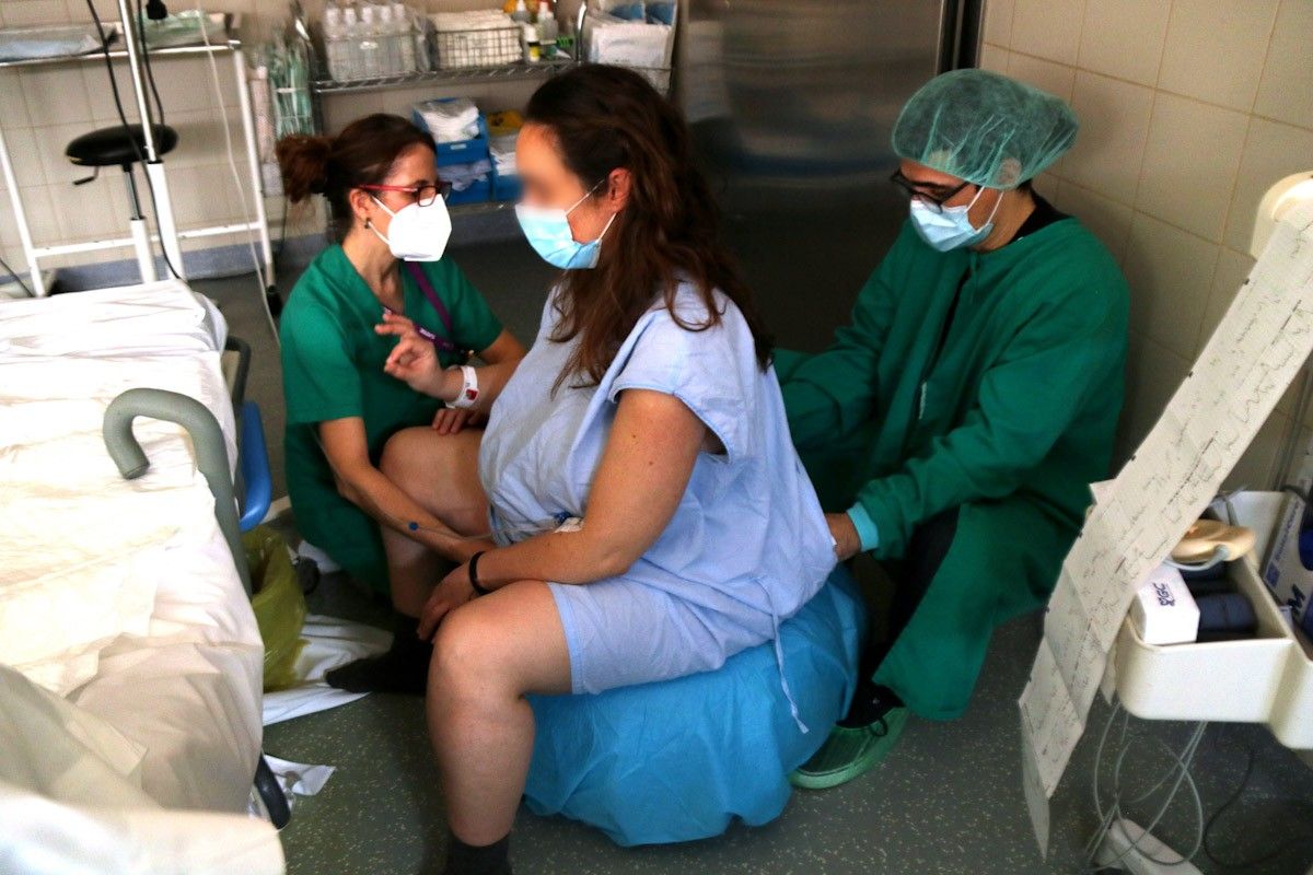 Una llevadora comprovant la situació d'una dona embarassada, minuts previs a donar a llum   