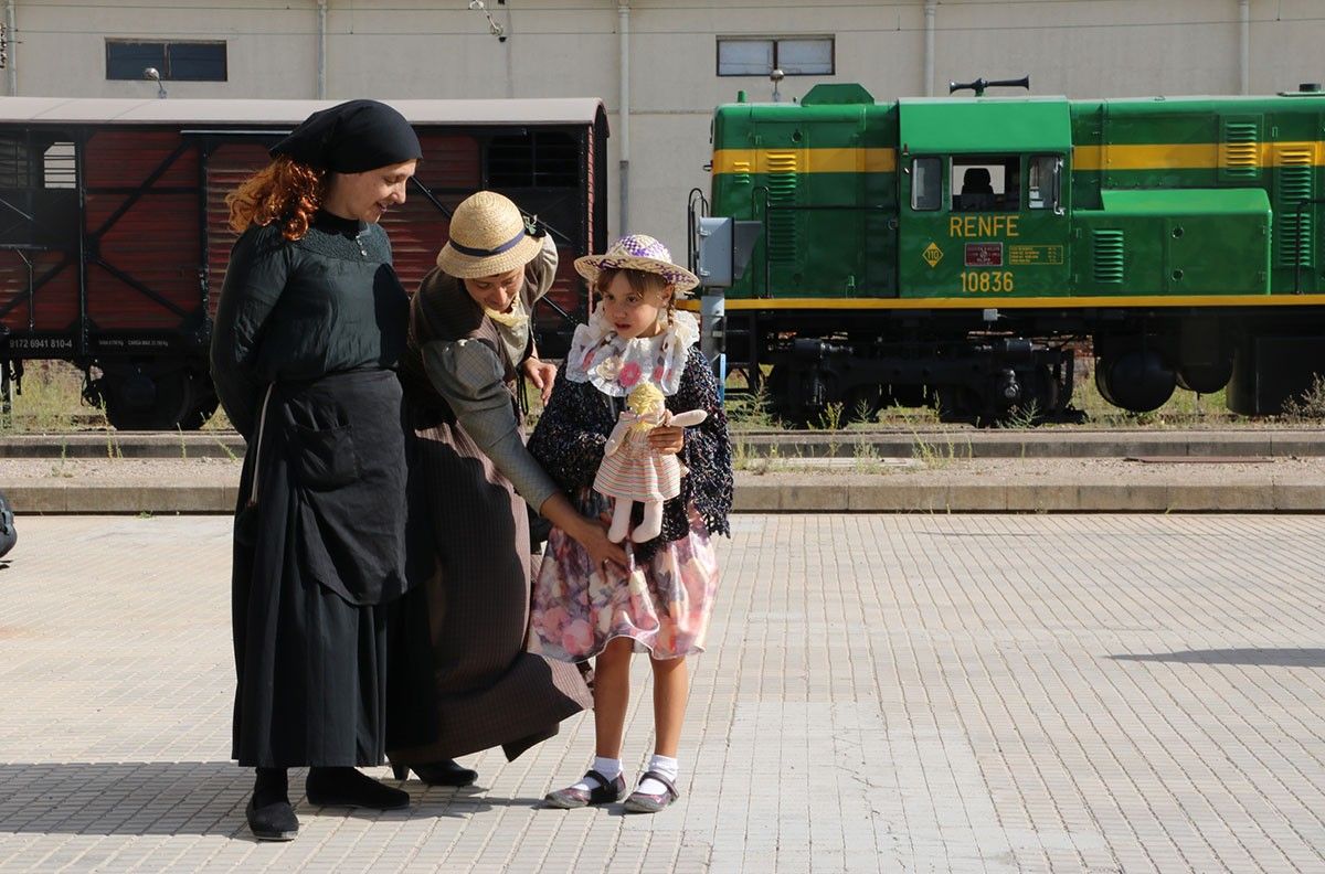 Dos dones i una xiqueta, vestides dels anys 50, davant de la locomotora 'yeyé'.