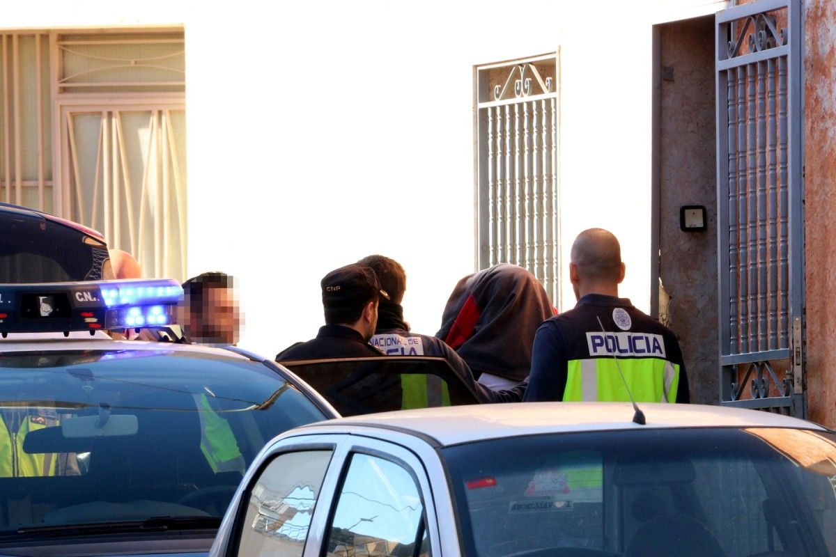 Agents de la policia espanyola s'emporten una de les persones detingudes després de l'escorcoll d'una casa al carrer Cánovas d'Amposta