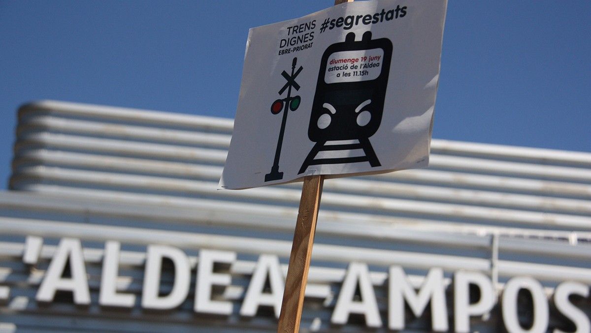 Un cartell que reclama 'Trens dignes' a les Terres de l'Ebre davant de l'estació de l'Aldea